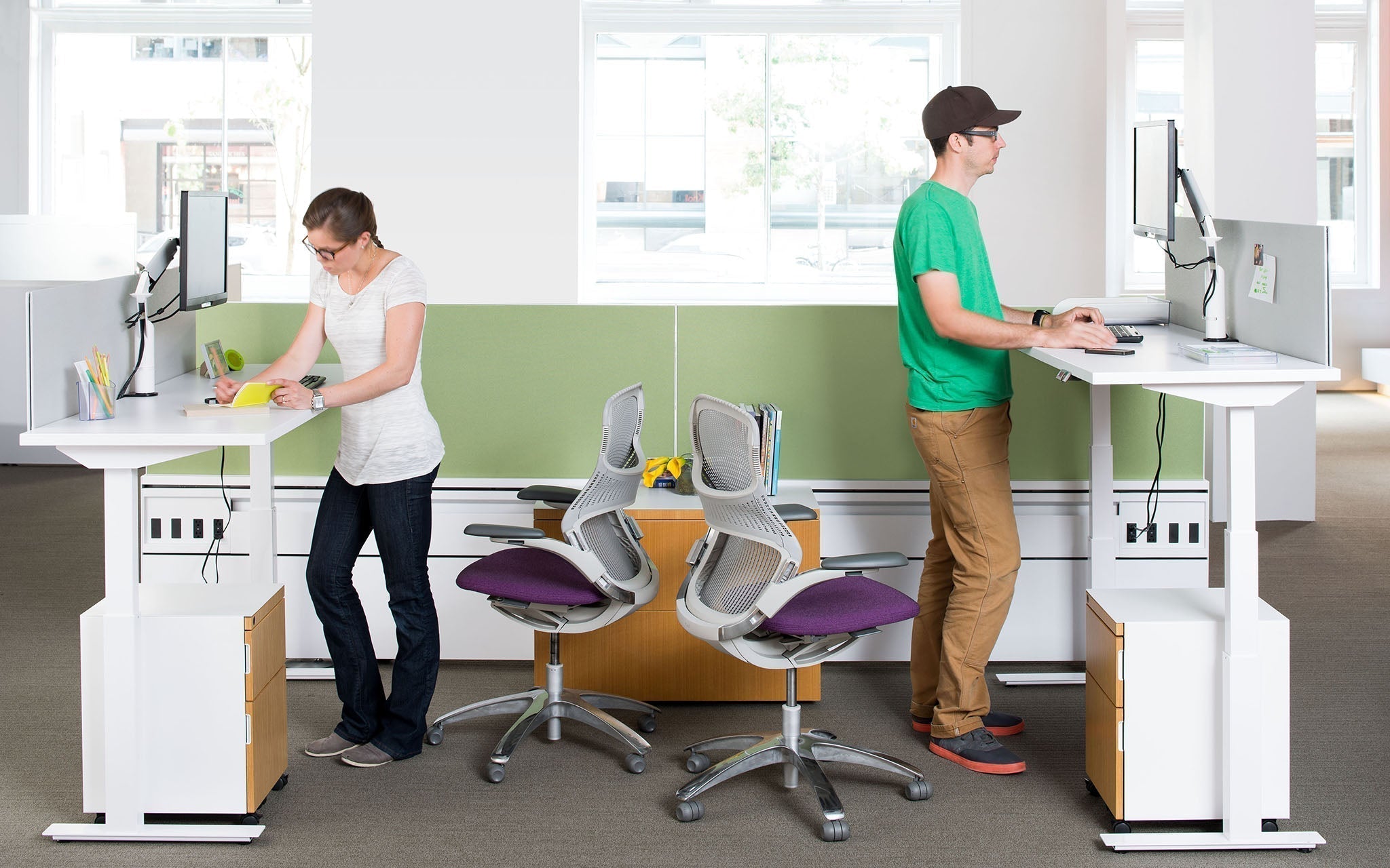 Two office workers using standing desks.