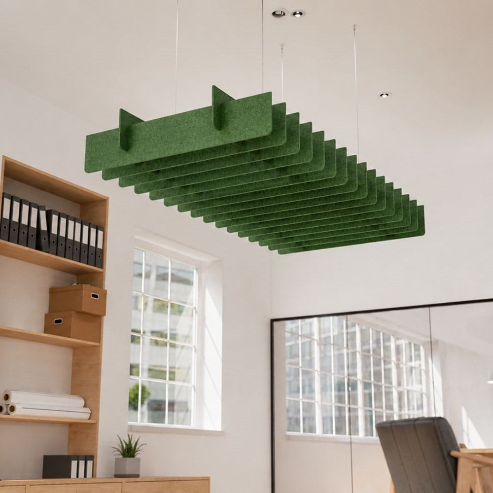 A green felt acoustic ceiling cloud suspended from the ceiling in a bright, modern office room with wooden shelving and windows.