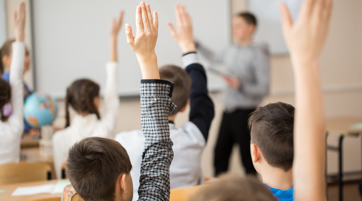 kids a classroom putting up their hands