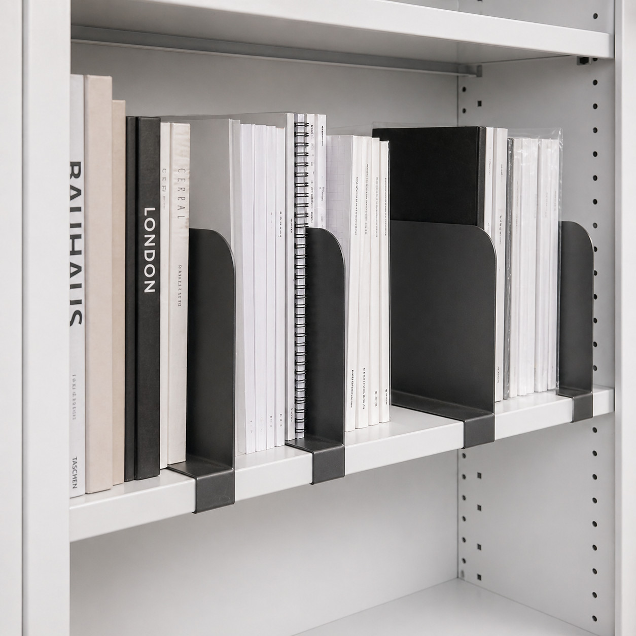White bookshelf with black metal dividers and white books on a white background