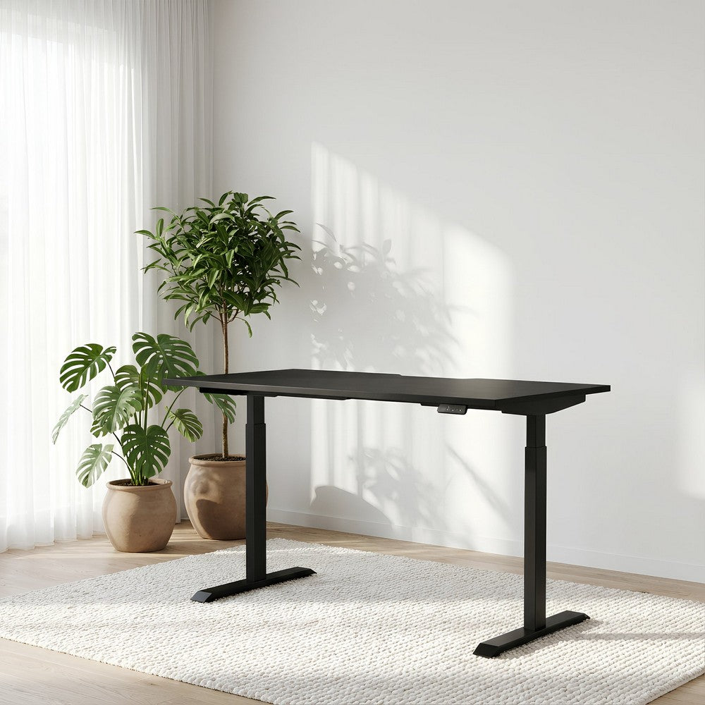 Black adjustable desk in a room with plants and light-colored walls